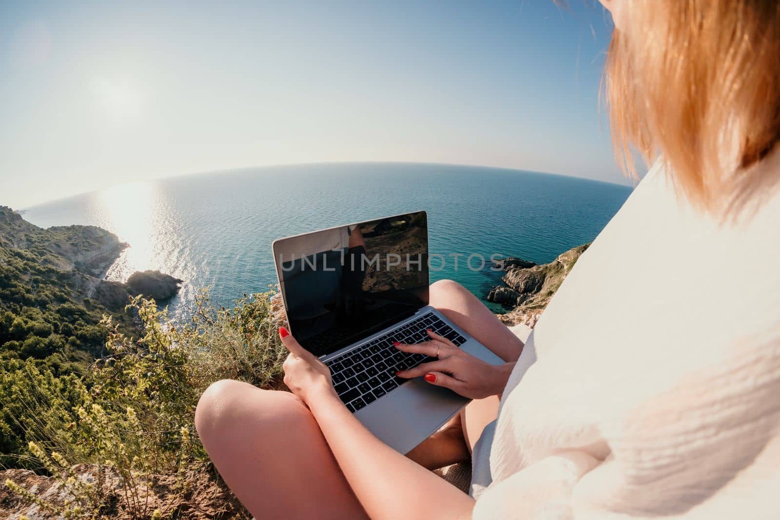 Woman sea laptop. Business woman in yellow hat working on laptop by sea. Close up on hands of pretty lady typing on computer outdoors summer day. Freelance, digital nomad, travel and holidays concept.