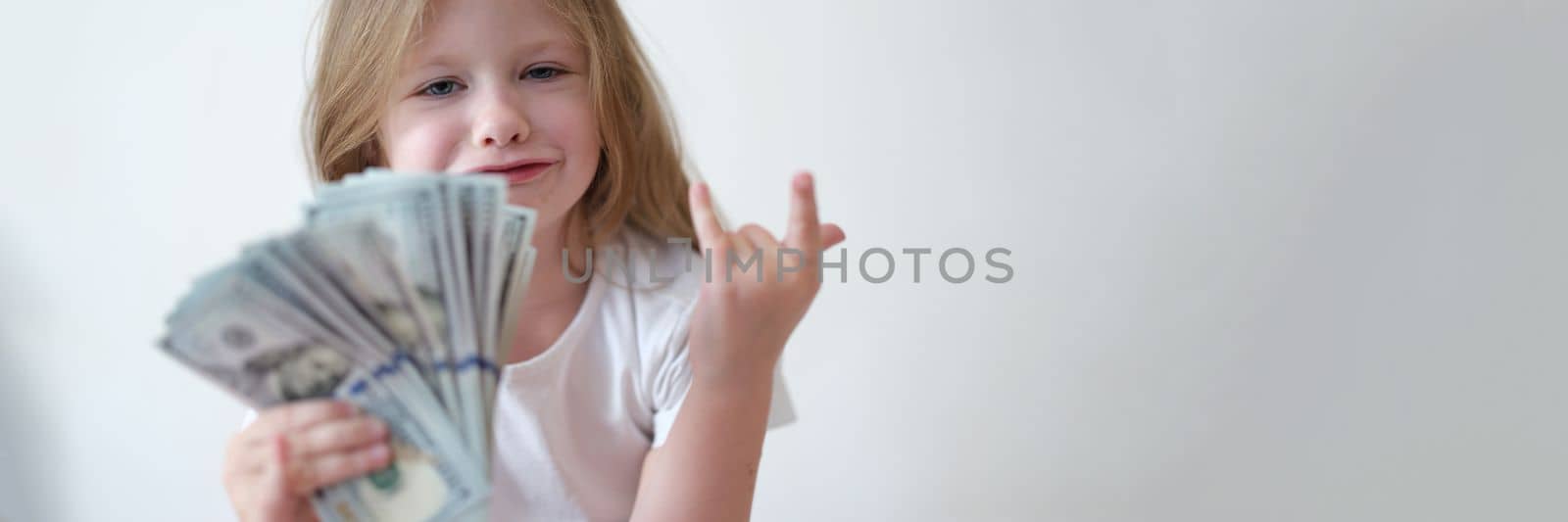 Happy little girl holding dollar bills. Child and financial expenses and earnings