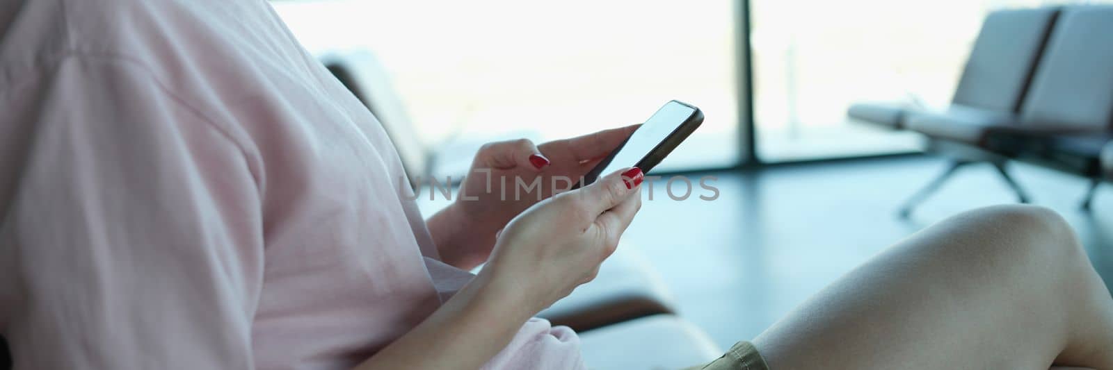 Woman holding smartphone sit at airport or train station. Making a travel itinerary through a mobile application concept