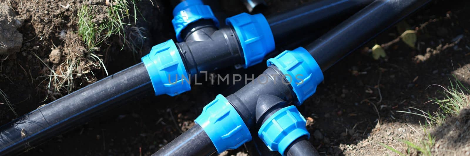 Black three way plastic water pipe on grass. Irrigation system in the garden concept