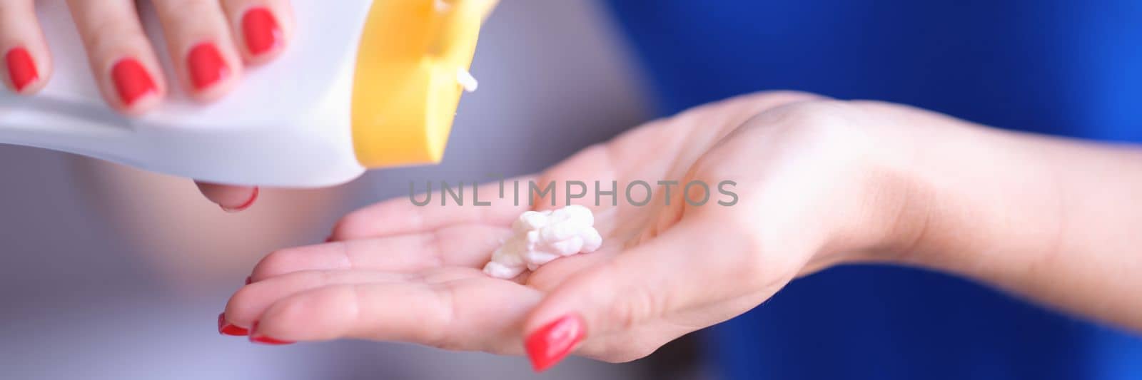 Female hands hold open cream tube and apply white cosmetic cream on healthy skin. Hand skin care concept