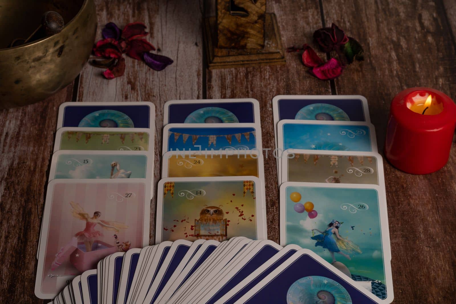 colorful tarot cards "oracle" lighted red candle and Tibetan bowl on a wooden table with copy space