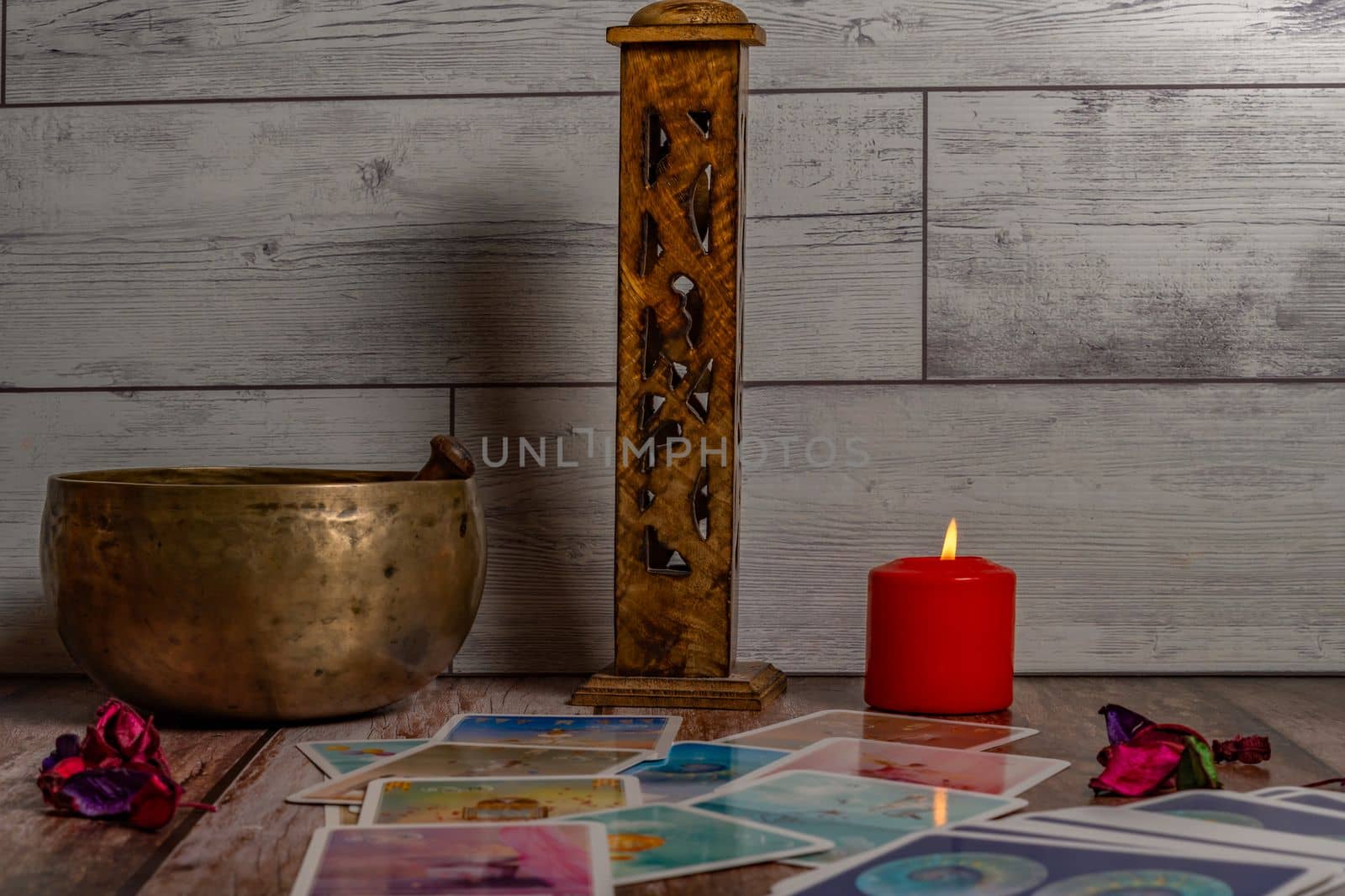 colorful tarot cards "oracle" lighted red candle, Tibetan bowl and incense burner on a wooden table and copy space