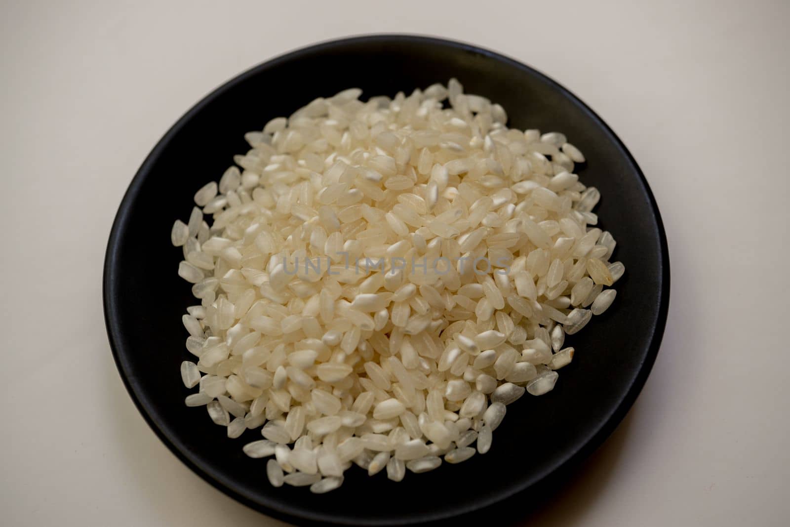 pile of rice on a black plate with a white background