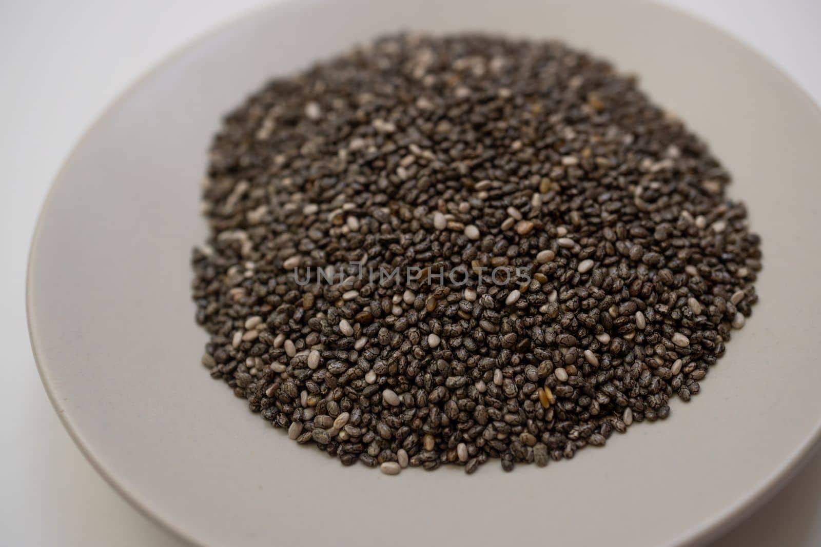 close-up of chia seeds on a white plate isolated on a white background