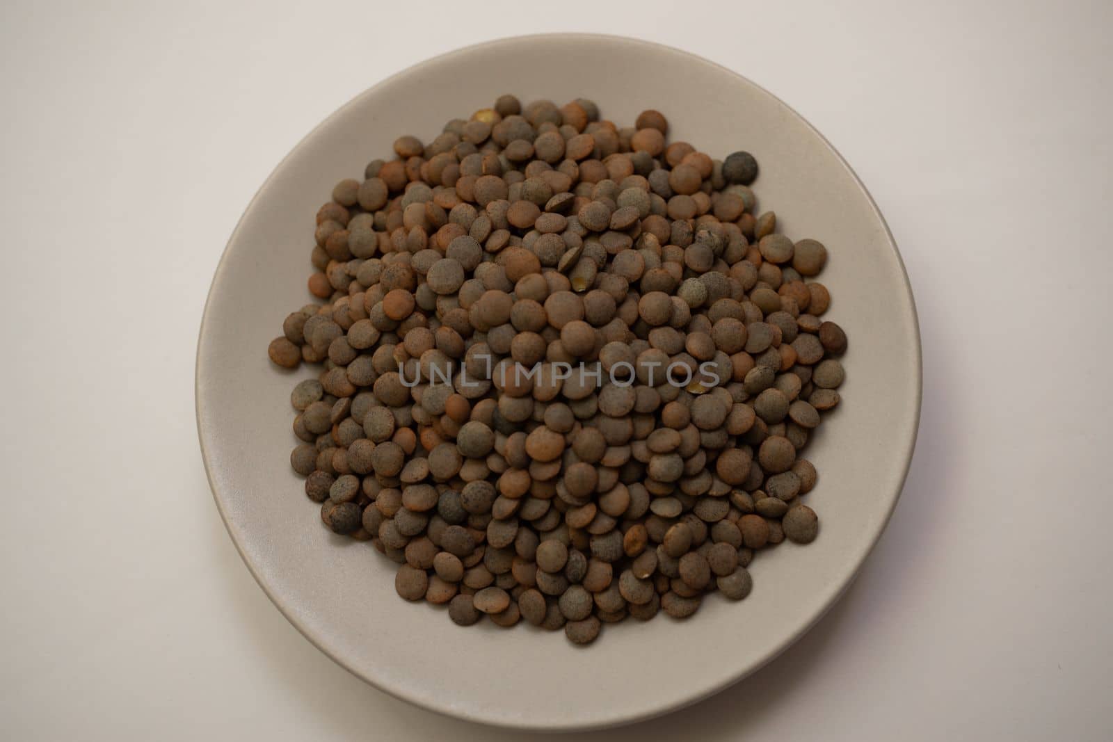 close-up of lentils on a white plate out of focus with white background