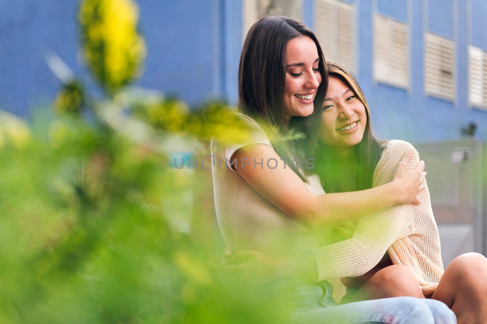 female couple embracing each other sitting in a city park, concept of friendship and love between people of the same sex, copy space for text