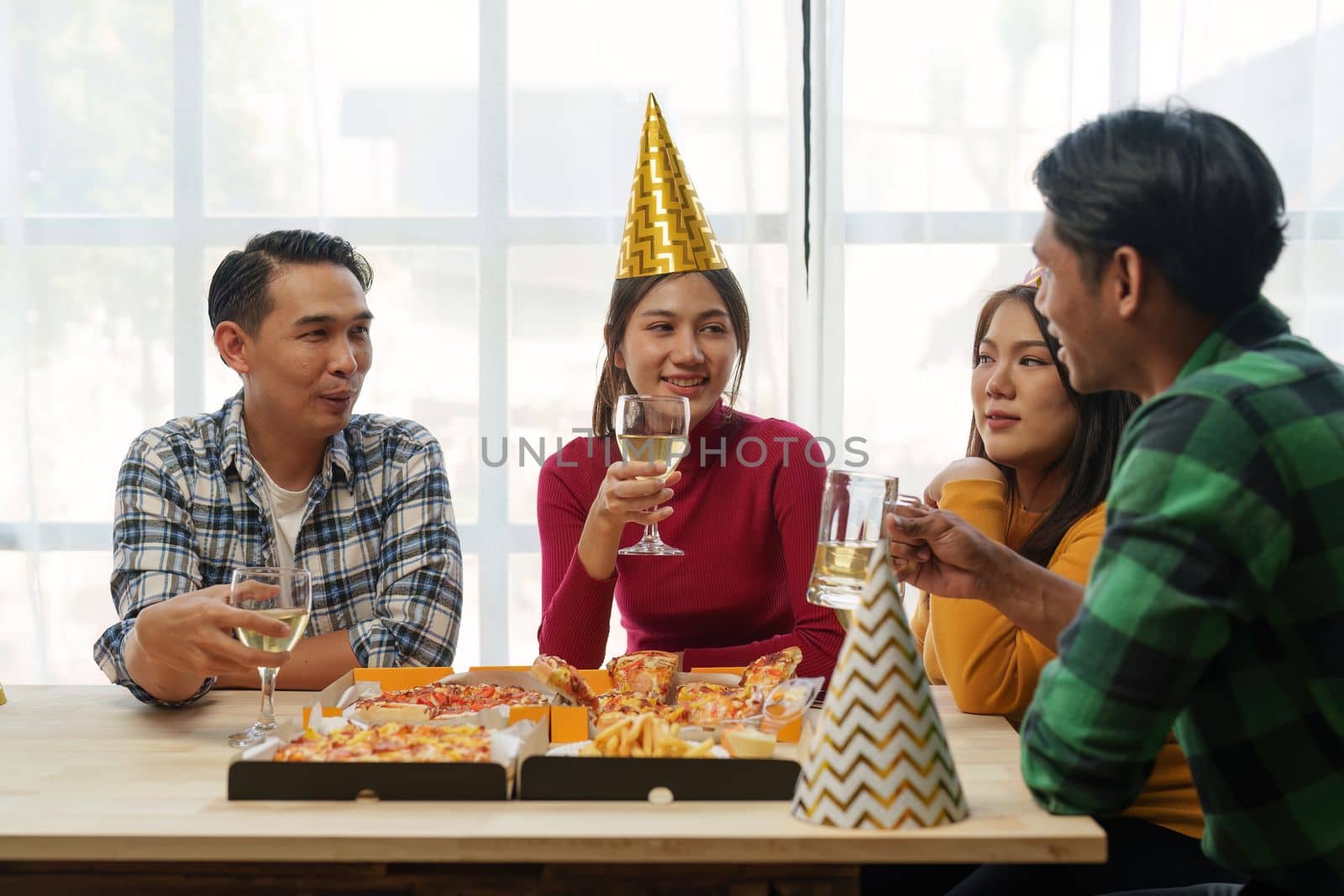 Friends at birthday party clinking glasses with champagne and pizza, enjoying Christmas vacation, pizza on the table. Holiday Party event