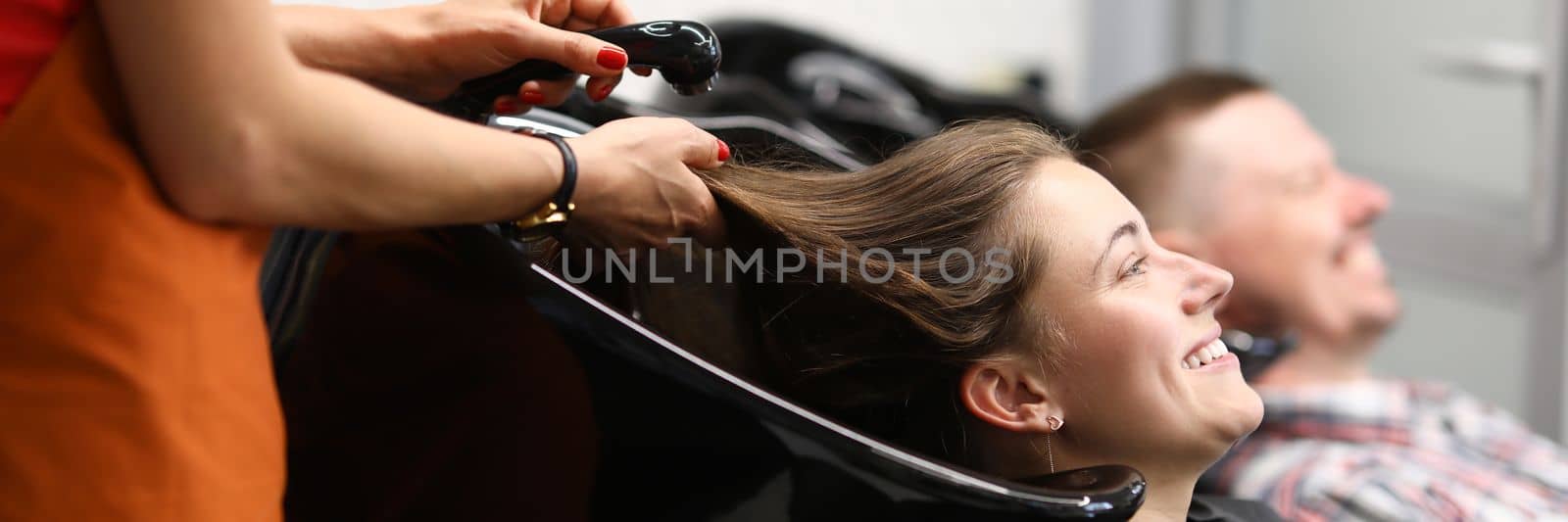 Beautiful happy smiling woman, professional hairdresser washes hair by kuprevich