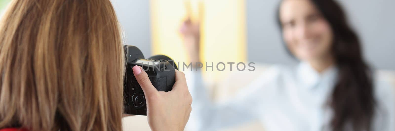 Woman photographer photographs model on camera at home by kuprevich