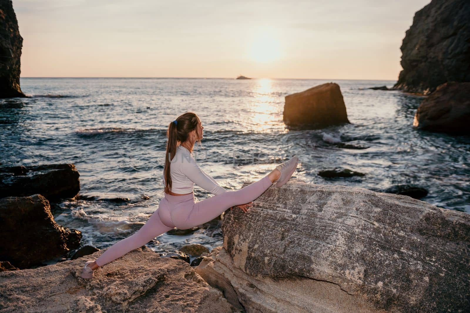 Young woman with black hair, fitness instructor in pink sports leggings and tops, doing pilates on yoga mat with magic pilates ring by the sea on the beach. Female fitness daily yoga concept