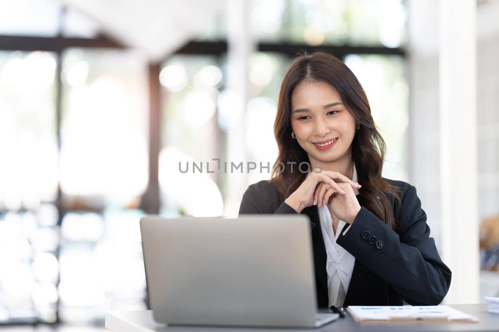 Charming Asian woman working at the office using a laptop Looking at the camera...