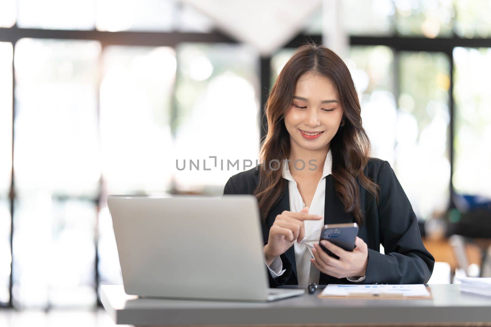 Charming Asian woman working at the office using a laptop Looking at the camera. by wichayada