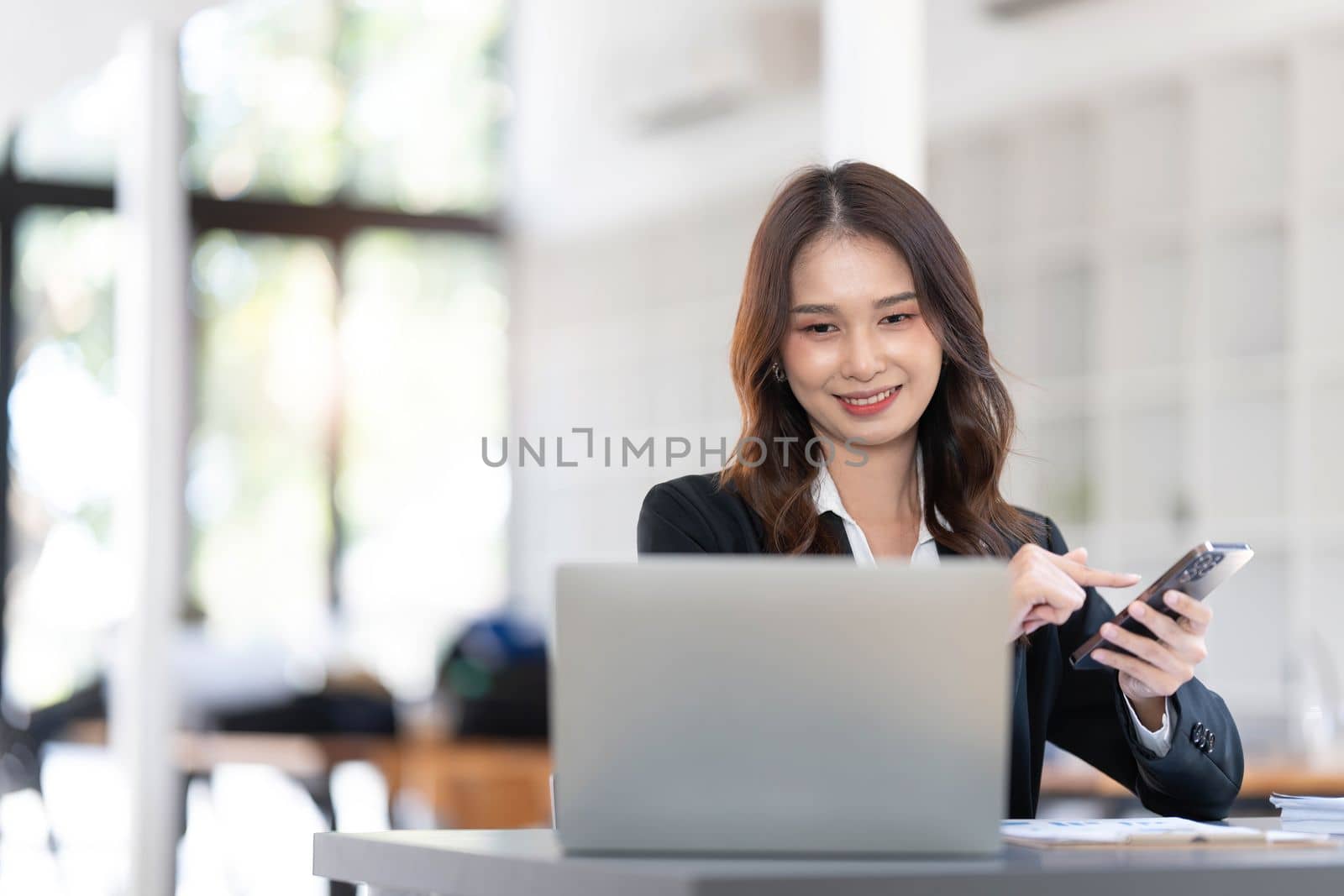 Charming Asian woman working at the office using a laptop Looking at the camera...