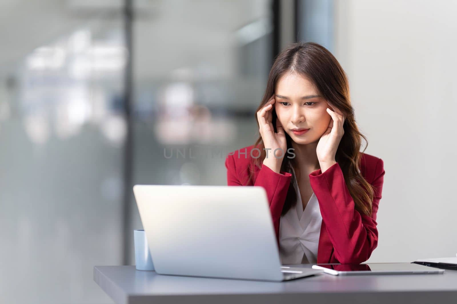 asian woman thinking hard concerned about online problem solution looking at laptop screen, worried serious asian businesswoman focused on solving difficult work computer task by wichayada