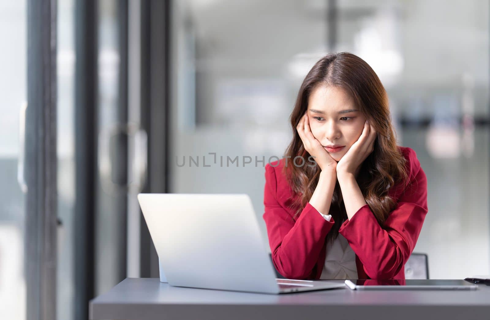 asian woman thinking hard concerned about online problem solution looking at laptop screen, worried serious asian businesswoman focused on solving difficult work computer task by wichayada