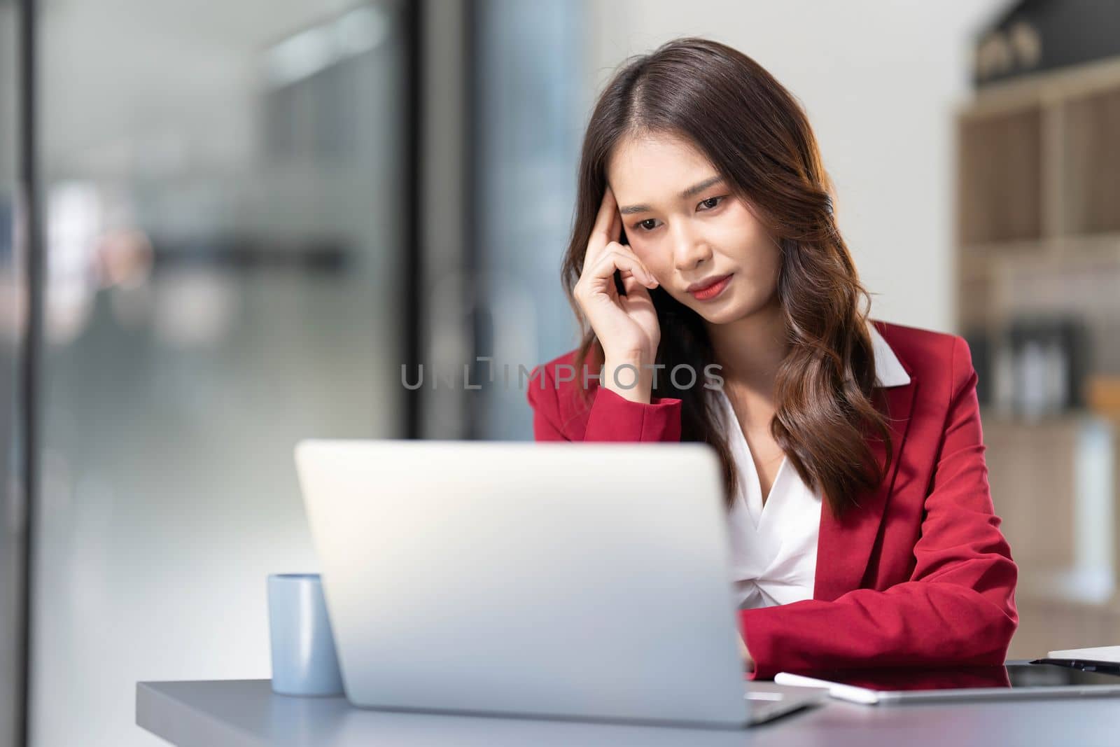 asian woman thinking hard concerned about online problem solution looking at laptop screen, worried serious asian businesswoman focused on solving difficult work computer task by wichayada