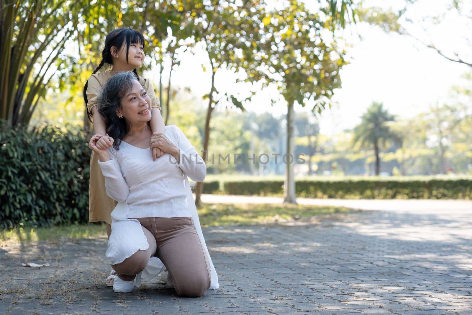 Happy granddaughter and her grandmother at summer park, family, leisure and people concept by nateemee