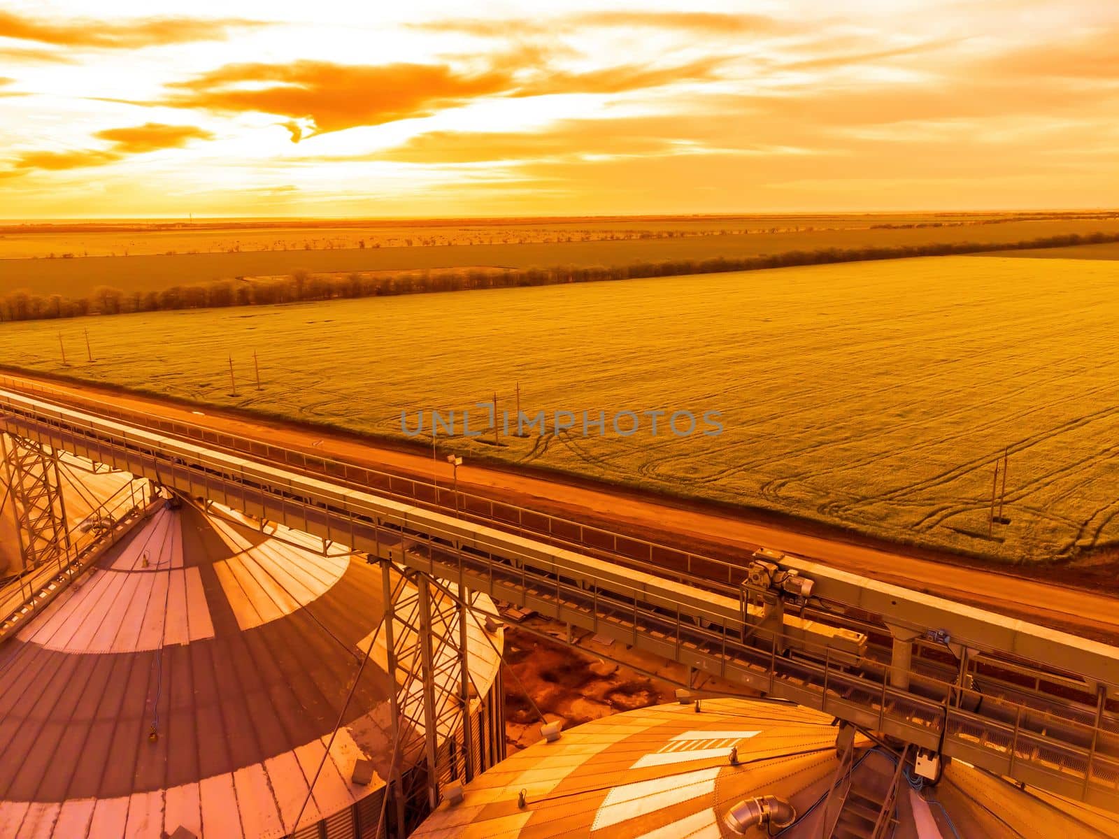 Grain elevator. Metal grain elevator in agricultural zone. Agriculture storage for harvest. Grain silos on green nature background. Exterior of agricultural factory