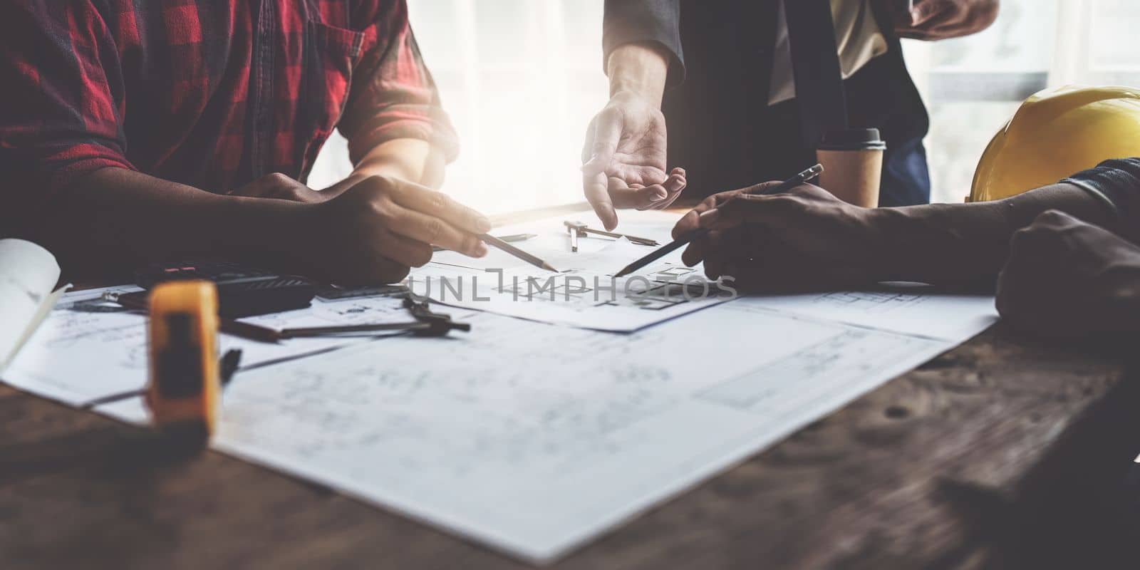 Close up of Architect team working with house model for architectural plan, engineer sketching a construction project, green energy concept.