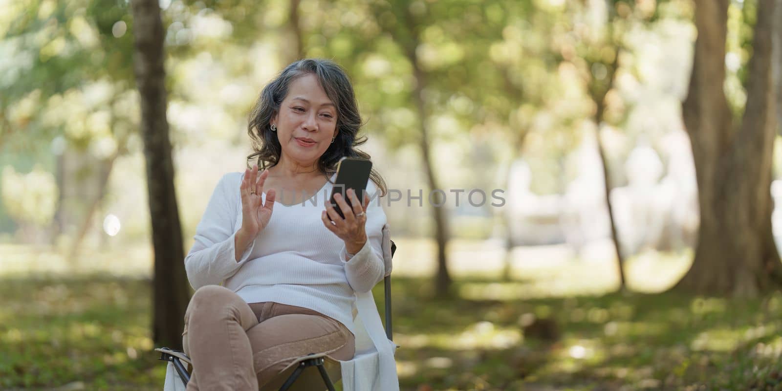 Happy senior asian woman at outdoor park and talking on video call with family by itchaznong