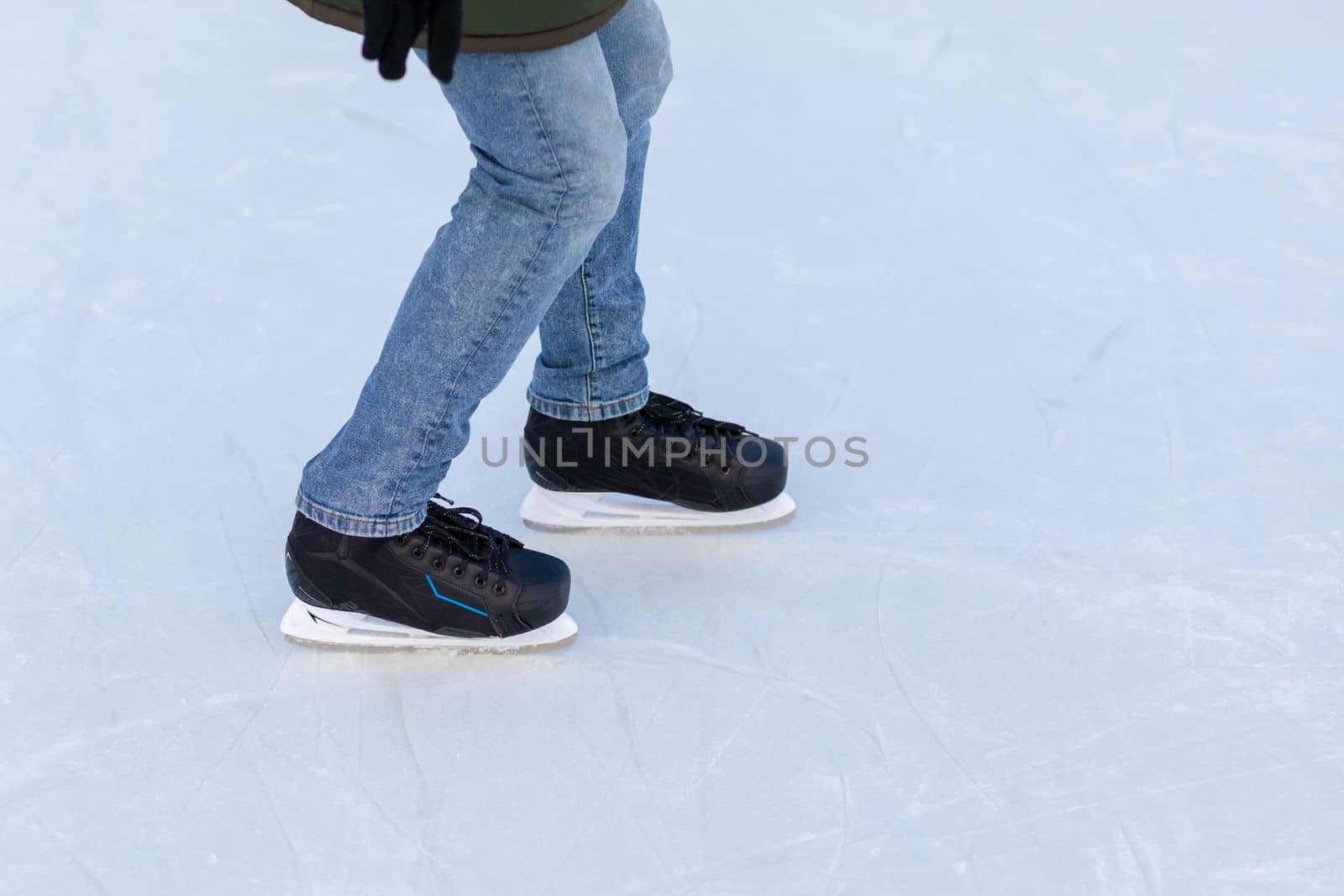 A pair of hockey skates with laces on frozen ice rink closeup. Ice skating or playing hockey in winter. ice and legs and copy space over ice background with marks from skating