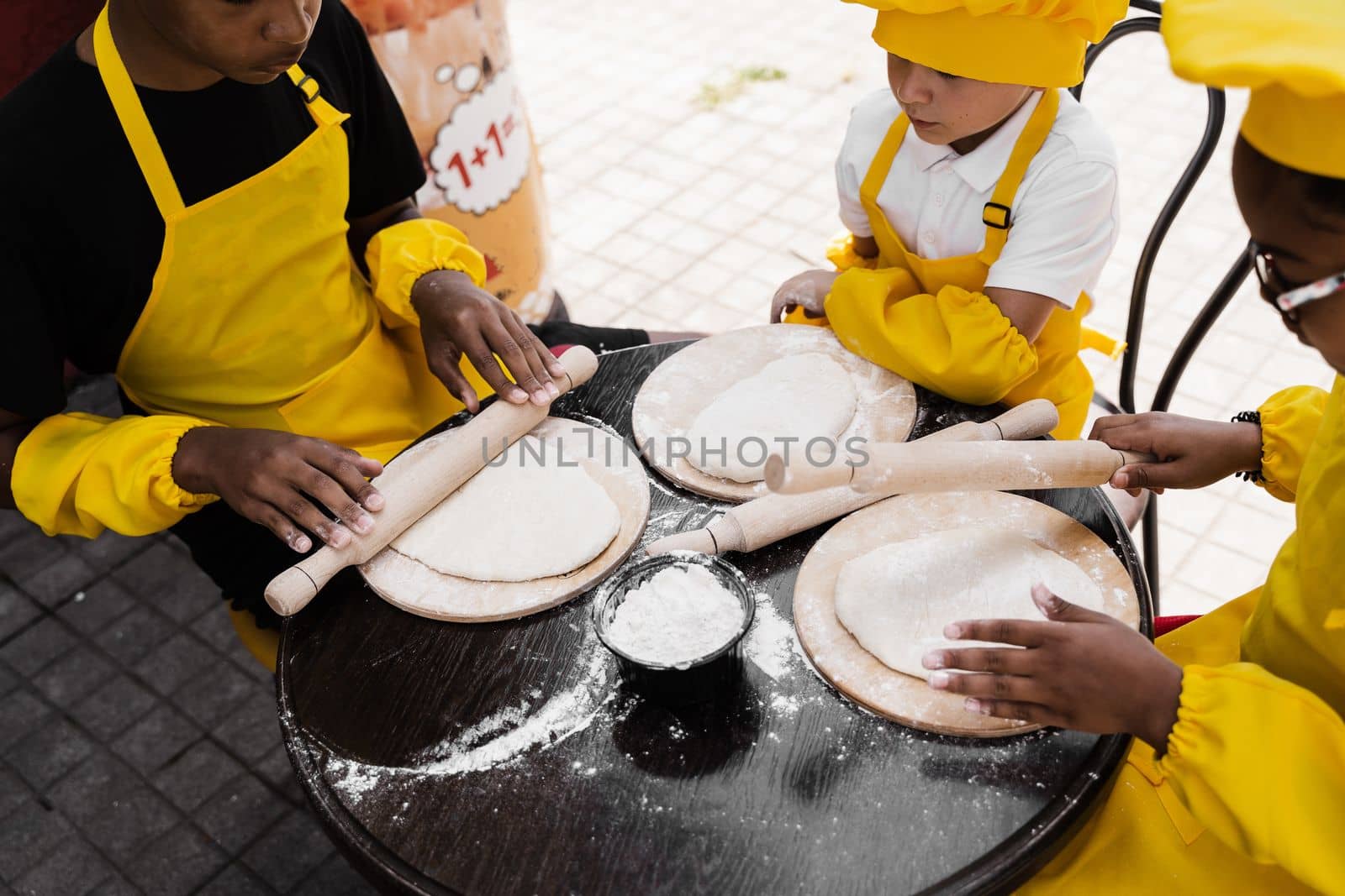 Multinational company of children cooks cooking dough close-up. Young cooks children cooking khachapuri