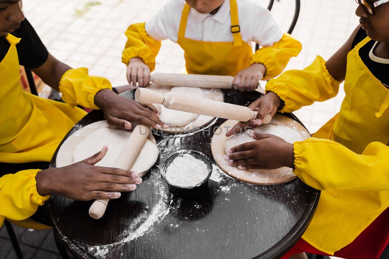 Multinational company of children cooks cooking dough close-up. Young cooks children cooking khachapuri