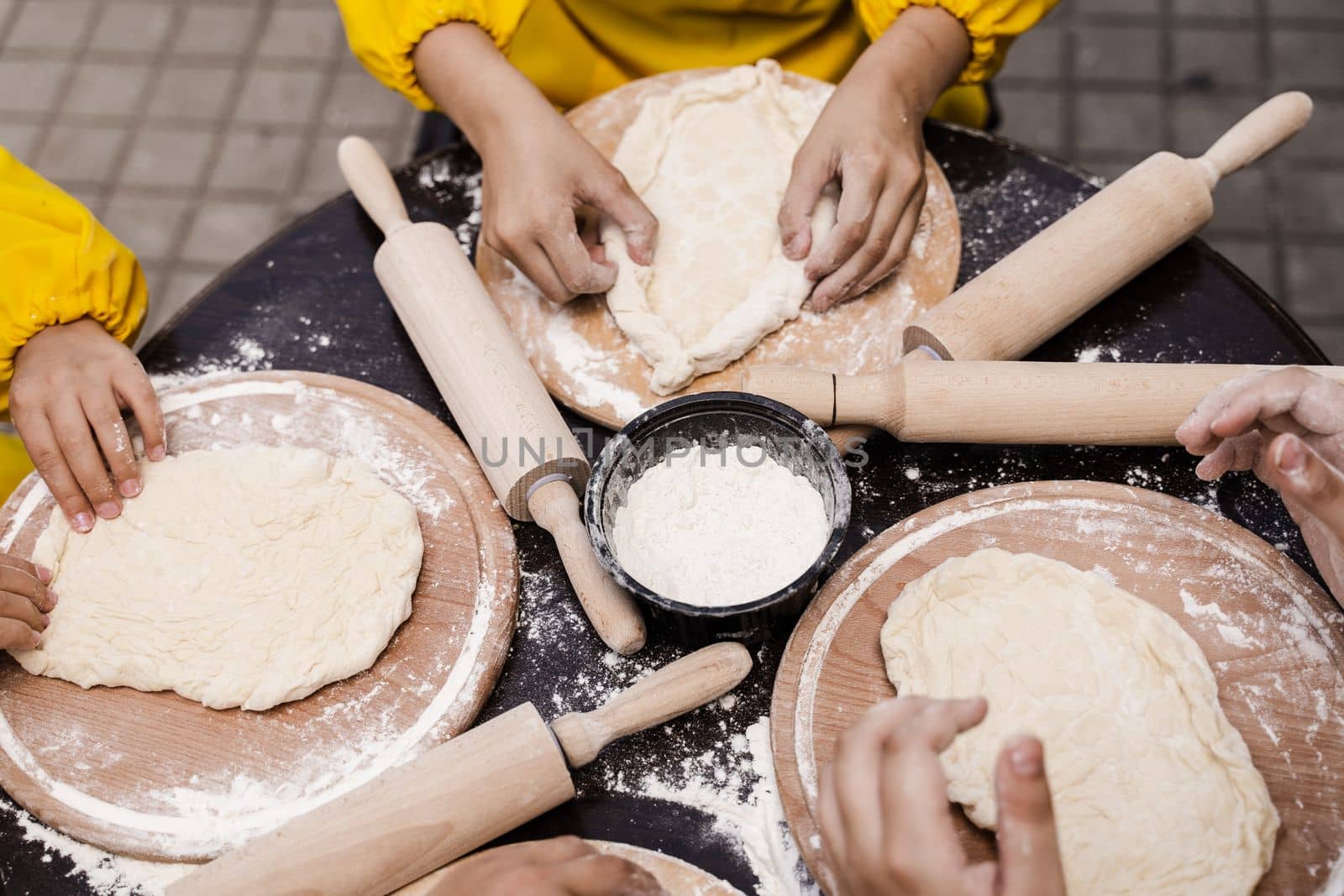 Multinational company of children cooks cooking dough close-up. Young cooks children cooking khachapuri. by Rabizo