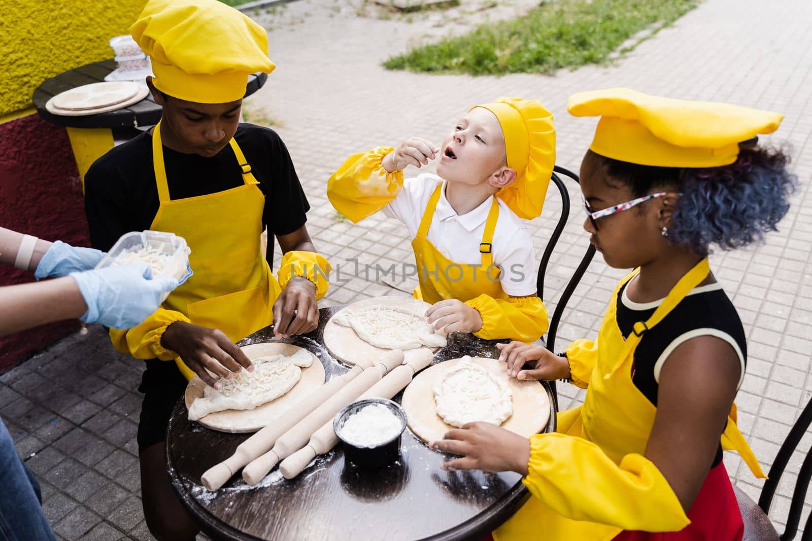Childhood cook activity of multinational children of black african and caucasian kids. Happy company of multiethnic children cooking dough