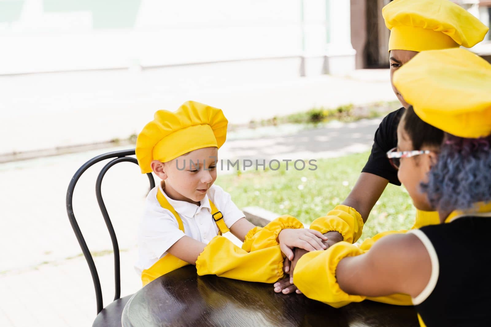 Multiracial children cook touching hands together forming pile. Friendship of multinational kids. Childhood. cooks in chefs hat and yellow apron uniform put hands on each other