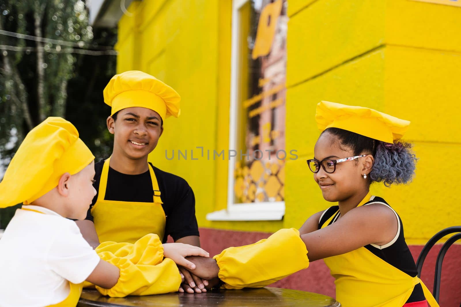 Multiracial children cook touching hands together forming pile. Friendship of multinational kids. Childhood. cooks in chefs hat and yellow apron uniform put hands on each other