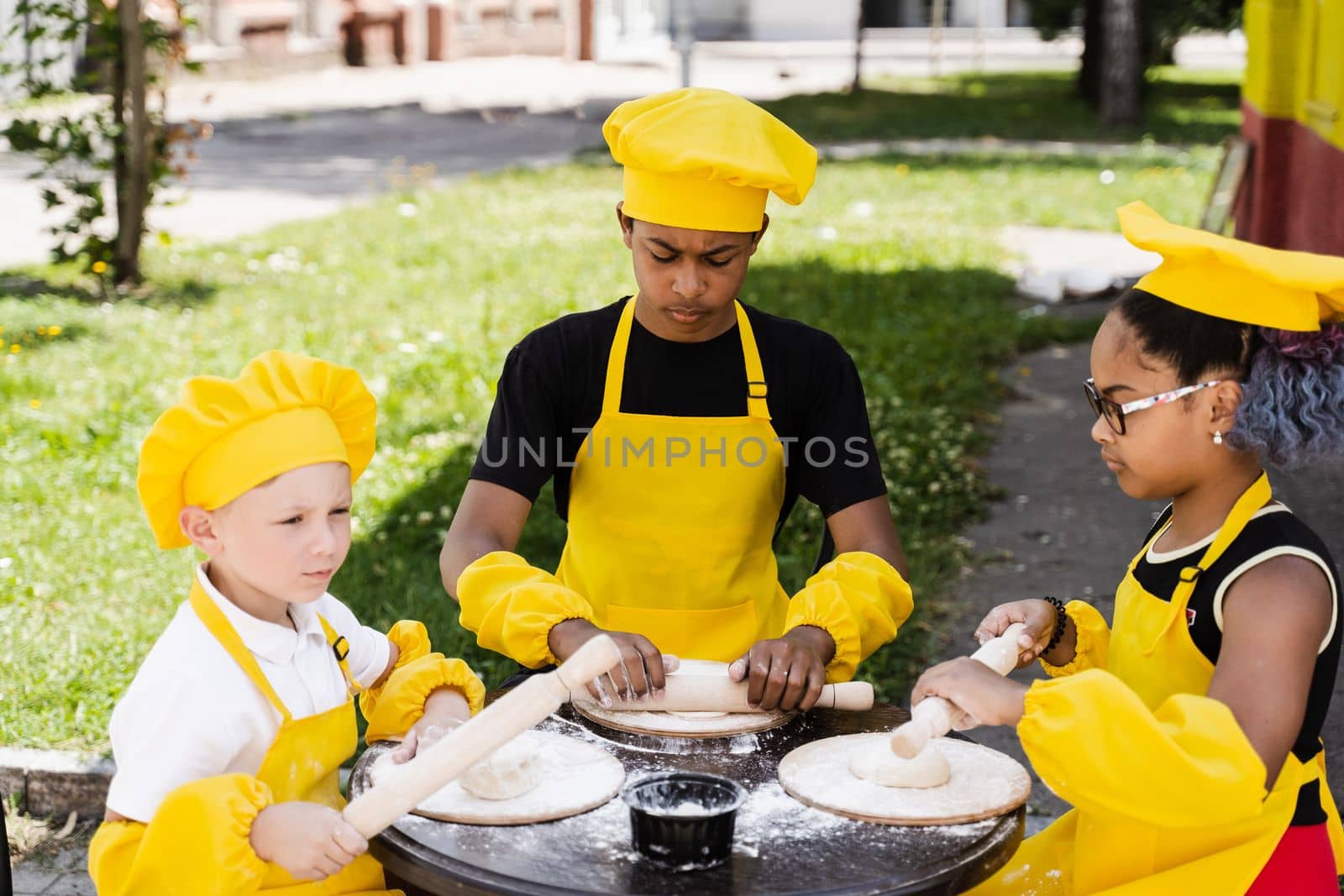Childhood cook activity of multinational children of black african and caucasian kids. Happy company of multiethnic children cooking dough