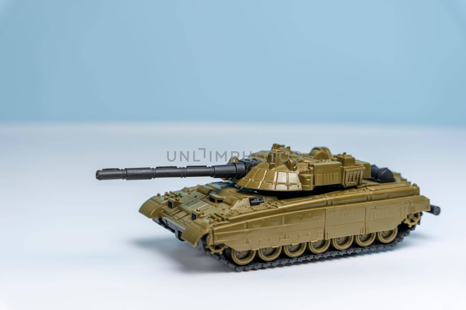 a children's toy military tank rides on the surface on a light background. Military actions. Heavy armored vehicles. Peacemakers.
