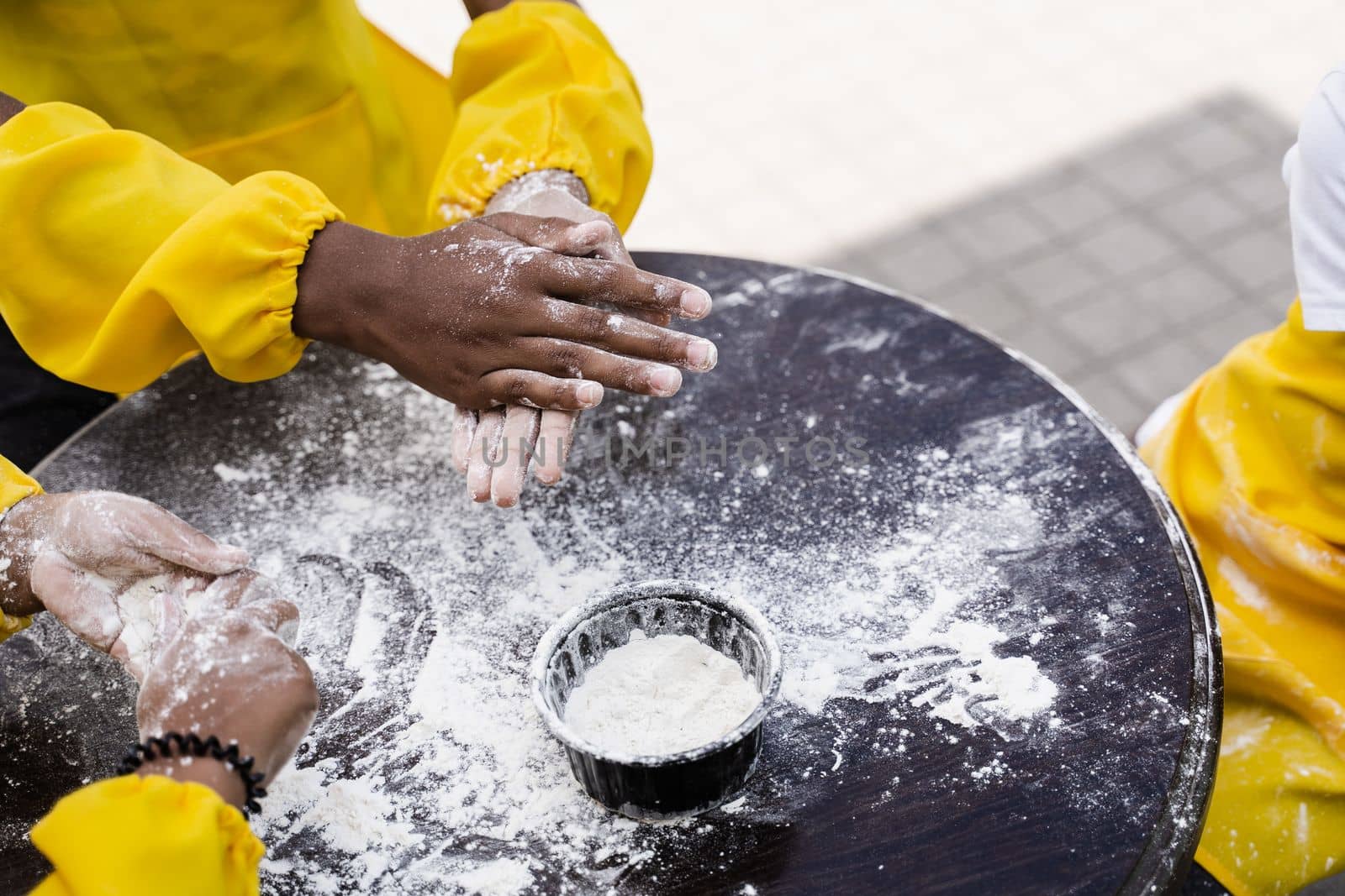 Hands of multinational children cooks play with flour for dough and having fun close-up. Young cooks children cooking khachapuri by Rabizo