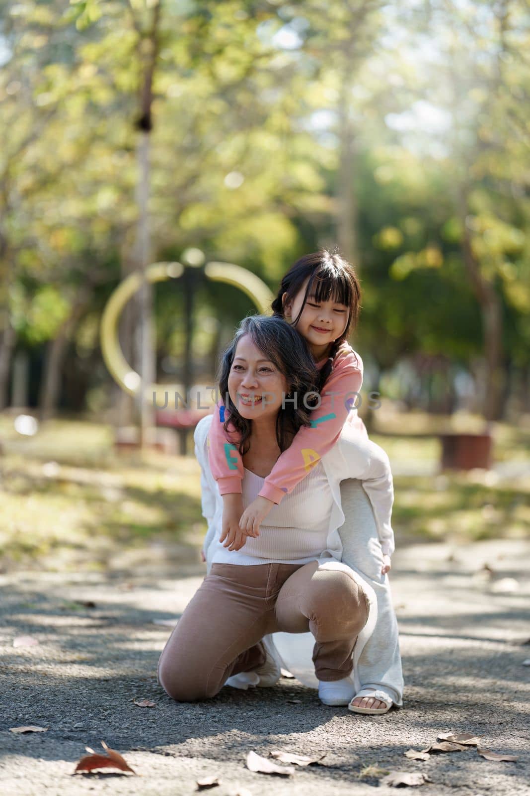 Asian Grandmother and Granddaughter hug together outdoor park. Hobbies and leisure, lifestyle, family life, happiness moment concept.