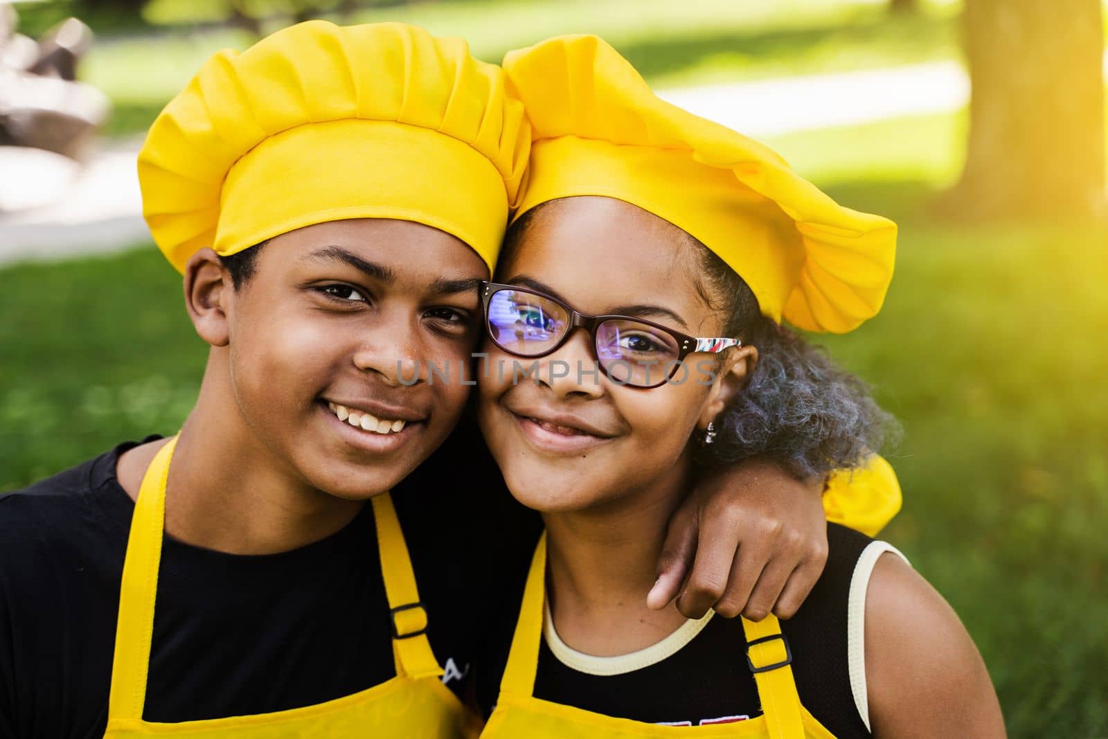 African children cooks in chefs hat and yellow uniforms smiling close-up portrait . African teenager and black girl have fun and cook food