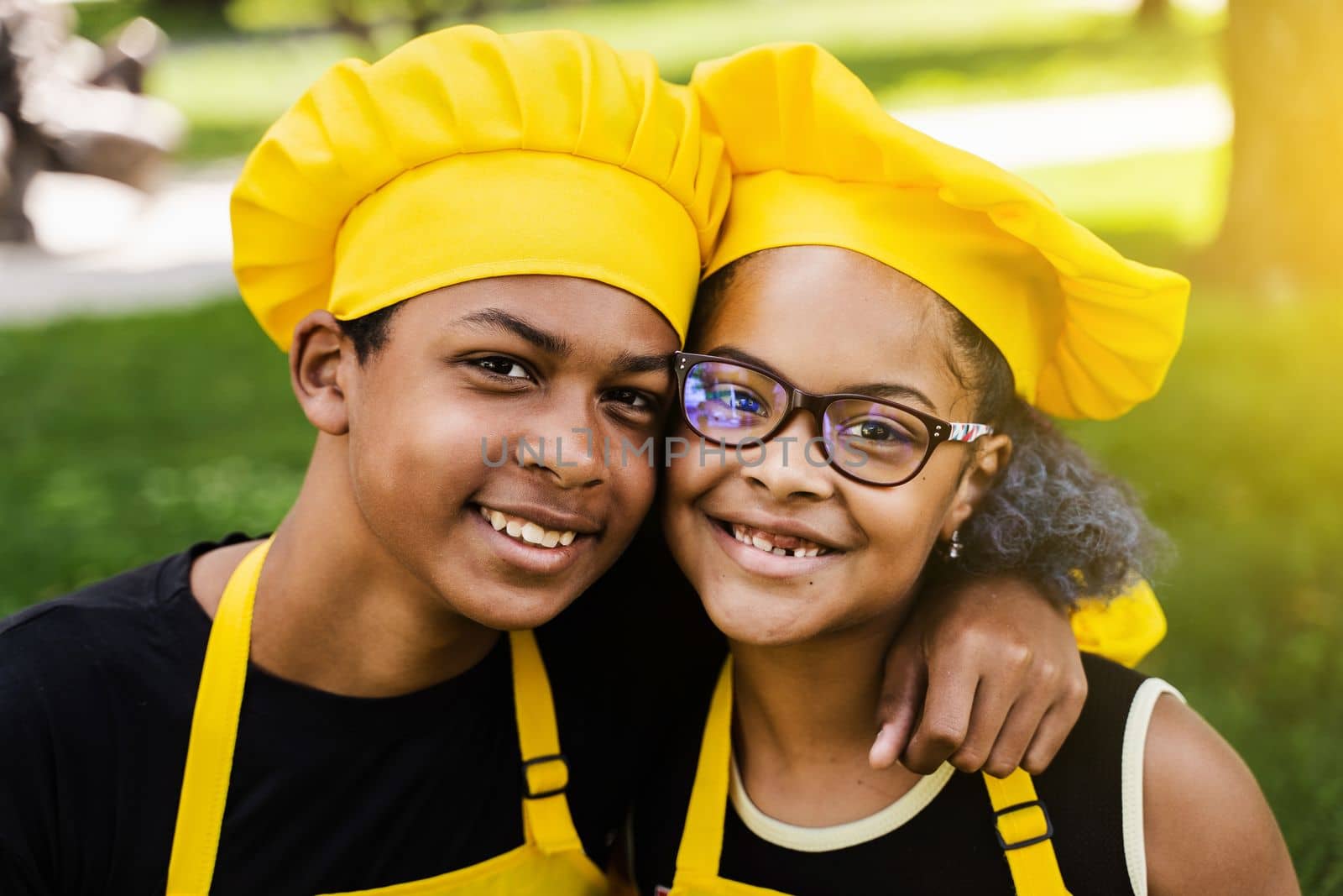 African children cooks in chefs hat and yellow uniforms smiling close-up portrait . African teenager and black girl have fun and cook food. by Rabizo