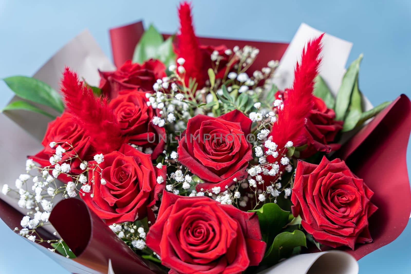 a beautiful bouquet of fresh red roses on a light blue background. Congratulations on Mother's Day. valentine's day. wedding