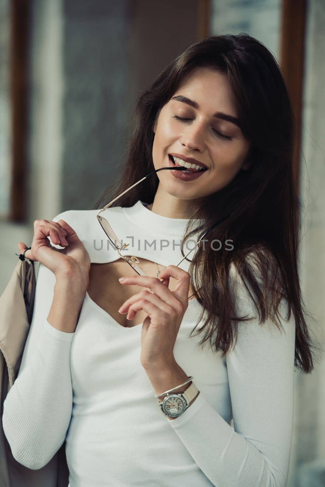 beautiful brunette girl in a sunglasses dressed in white blouse with a beige coat in hands. Stylish trendy fashion outlook by Ashtray25