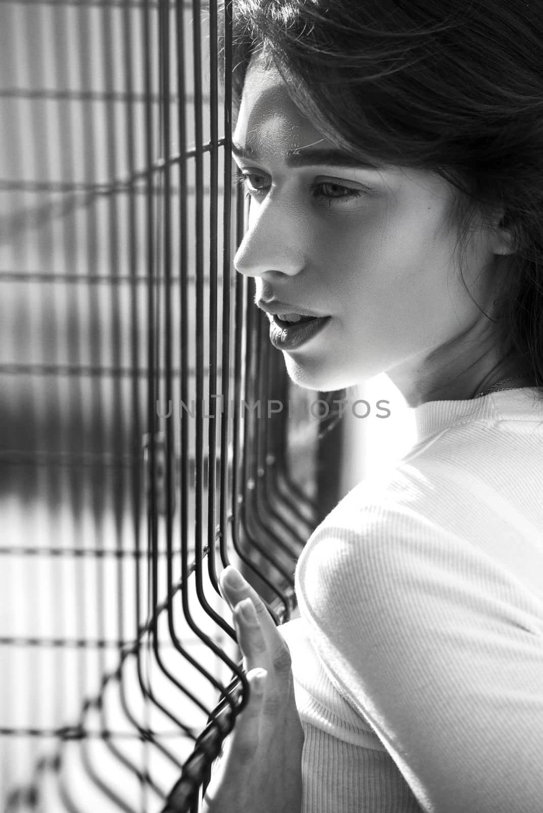 Close-up portrait of woman a in a white blause near a metal grid by Ashtray25