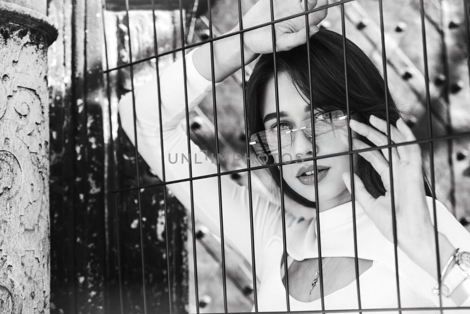 Close-up portrait of woman a in a white blause near a metal grid.