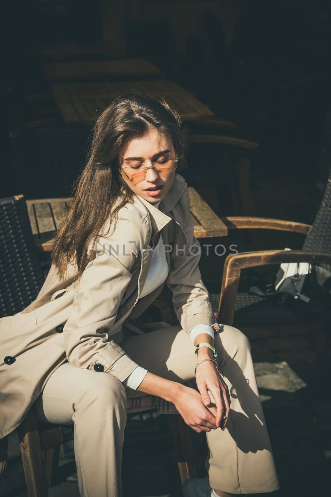 beautiful brunette girl in a sunglasses dressed in white blouse and beige coat posing in a chair. Stylish trendy fashion outlook by Ashtray25