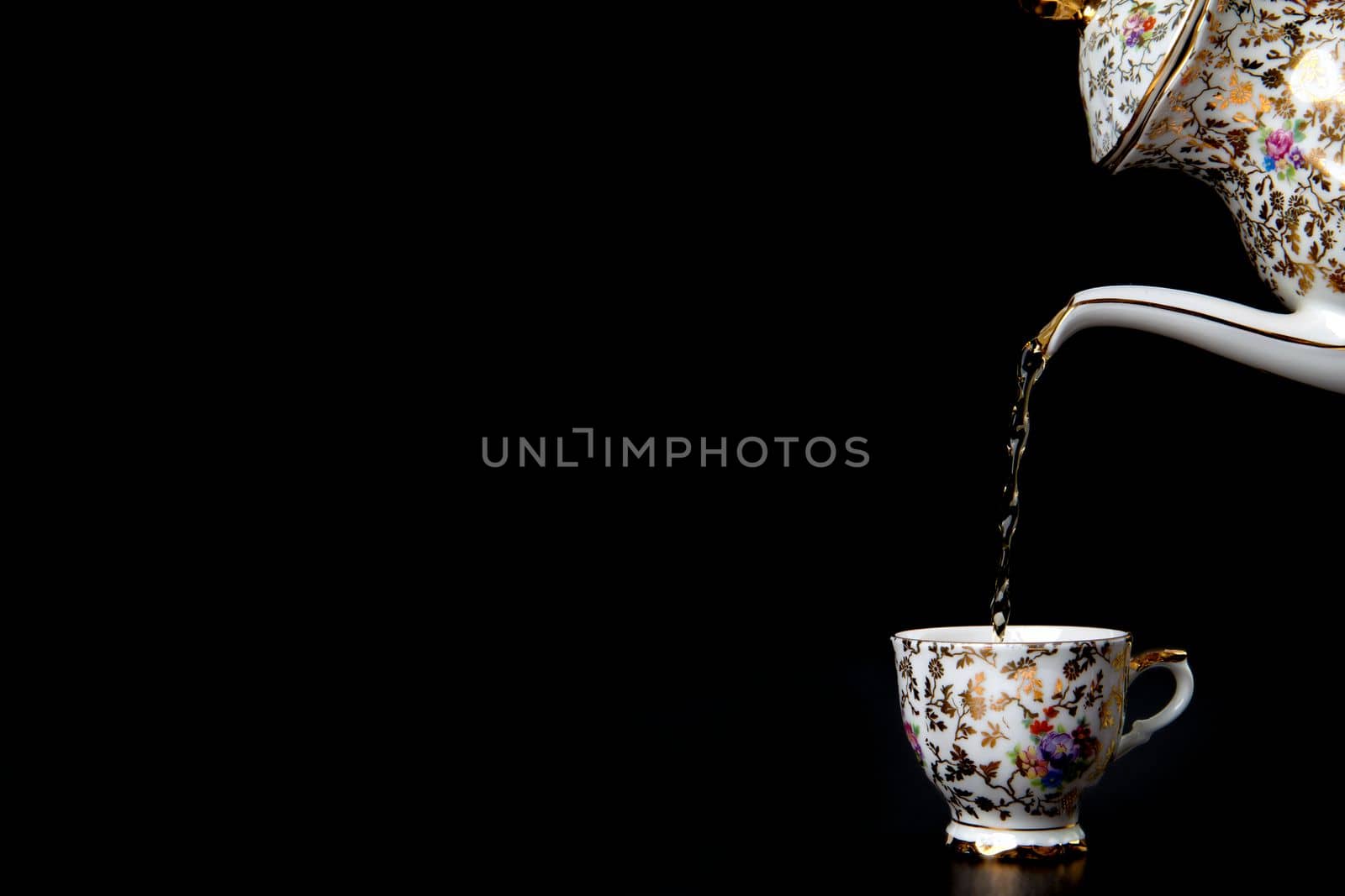 Pouring hot tea in vintage cup on black background, liquid movement in a cup, Antique crockery with copy space by Annebel146