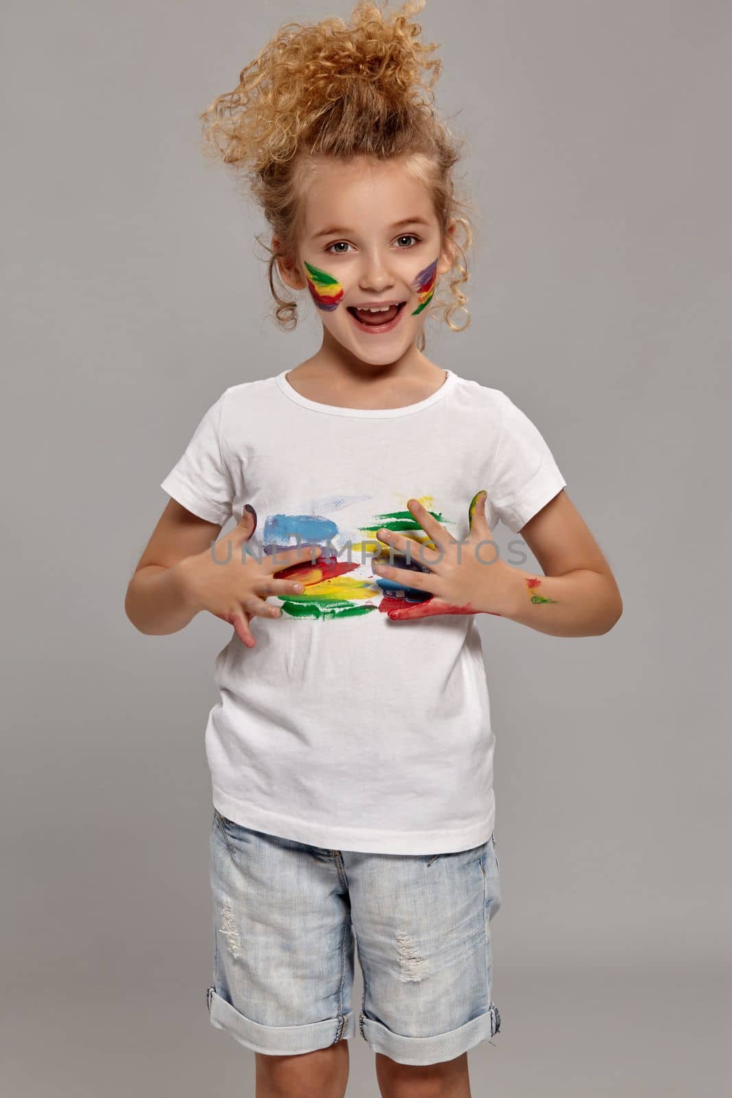 Nice teenager having a brush in her lovely haircut, wearing in a white t-shirt. She is smearing her t-shirt and looking excited on a gray background.