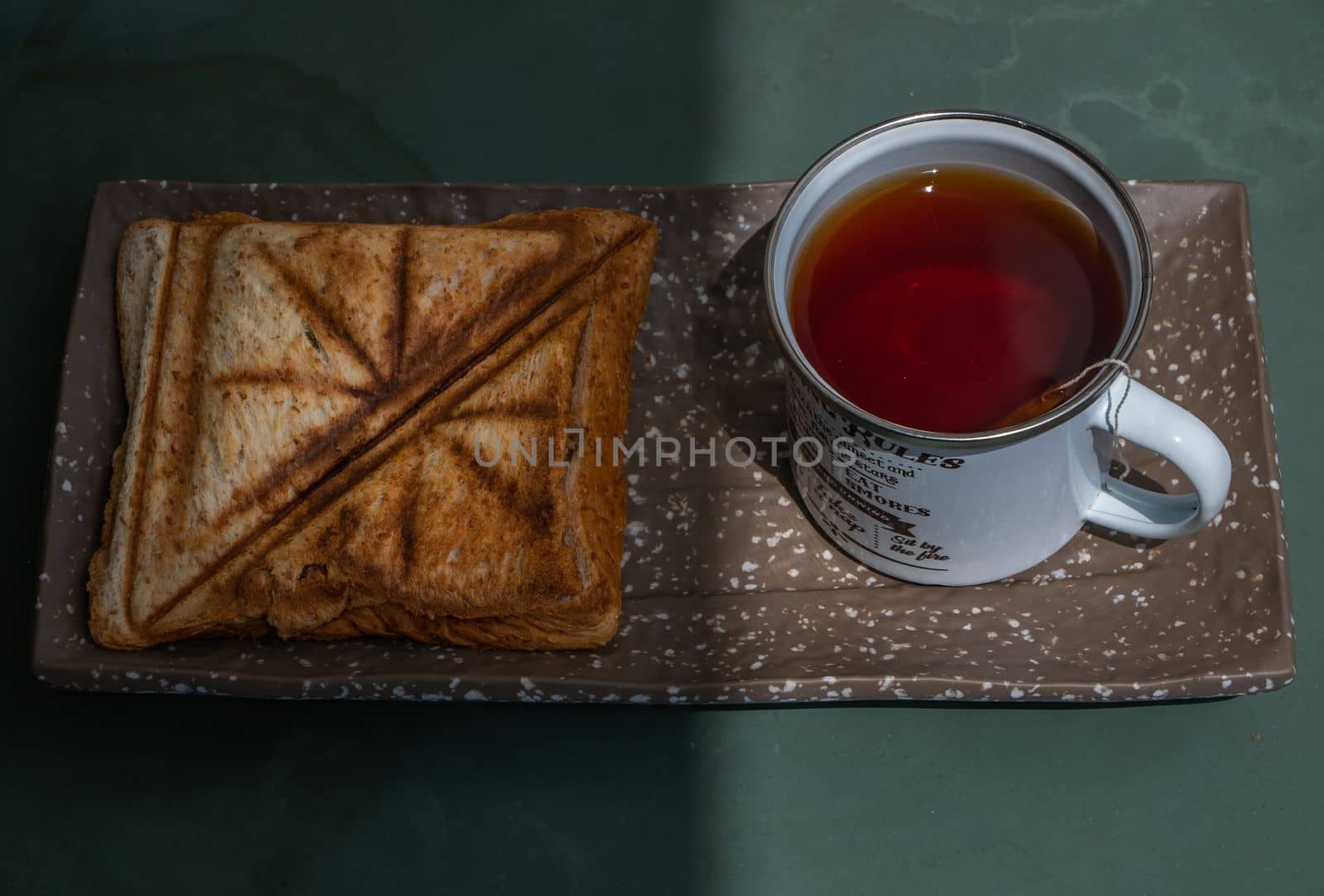 Breakfast - sandwiches and Cup of tea on a ceramics salver. Oblique view from the top.