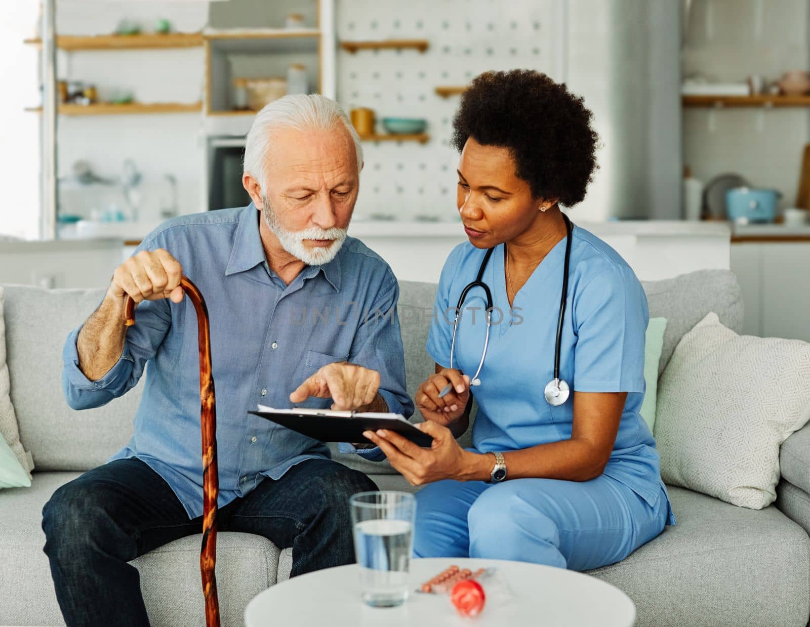 Doctor or nurse caregiver with senior man holding walking cane at home or nursing home