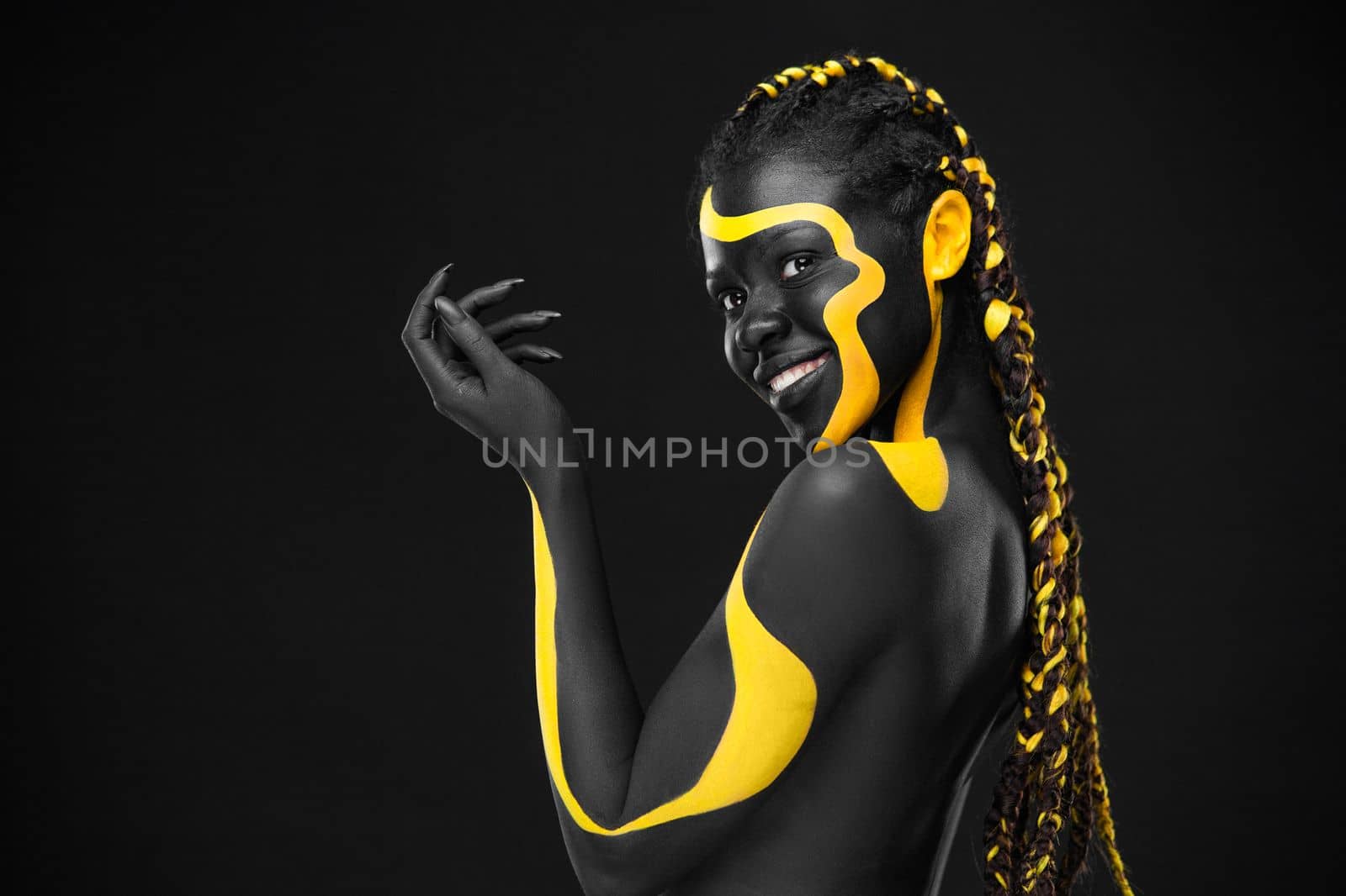 The Contemporary Art Face. Inspiration and idea for trendy magazines. Black and yellow body paint on african woman. An amazing model with makeup and bodyart