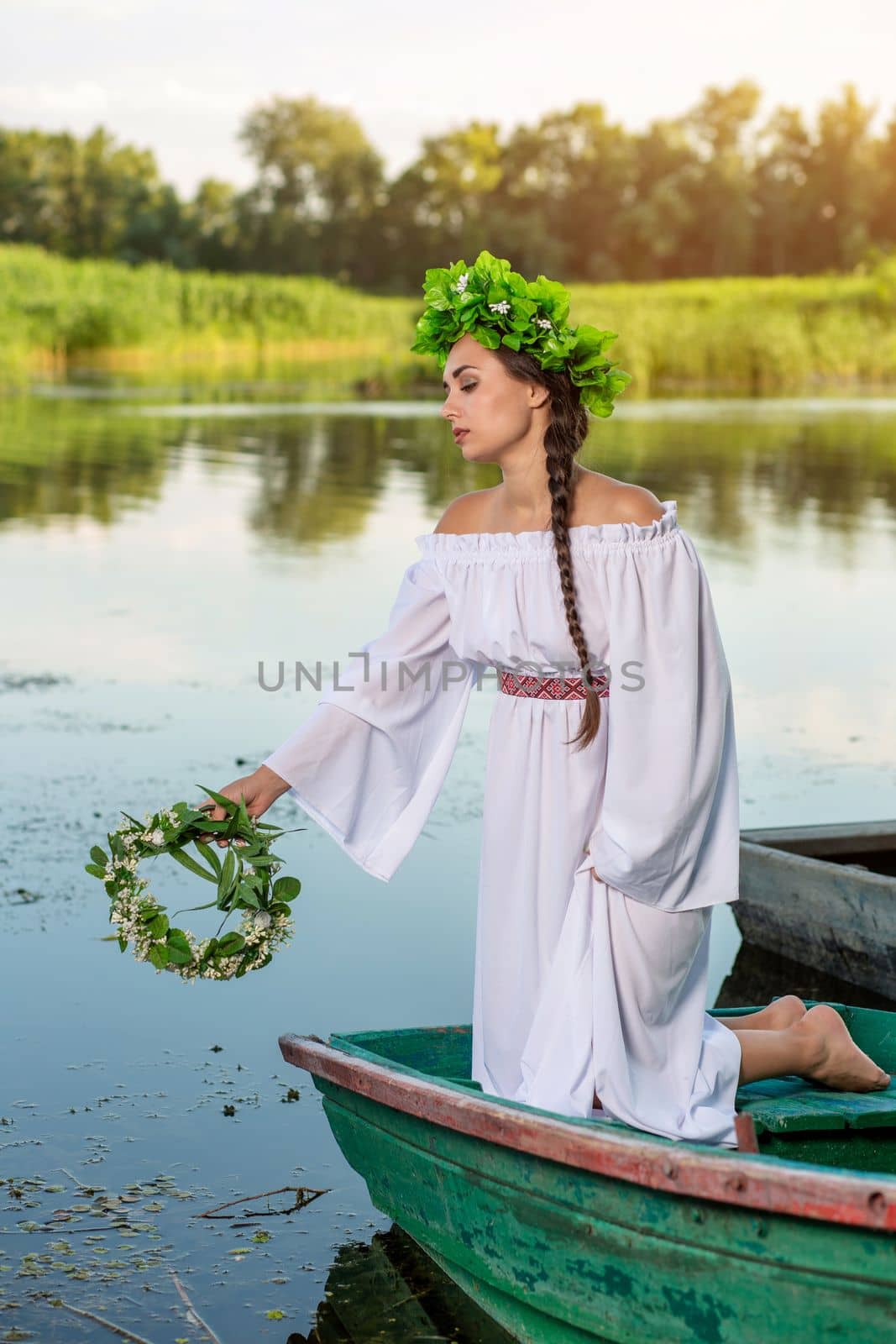 Young sexy woman on boat at sunset. The girl has a flower wreath on her head, relaxing and sailing on river. Fantasy art photography. by nazarovsergey