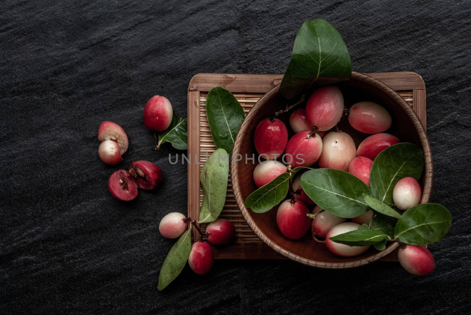 Bengal-Currants, Carandas-plum or Karonda fruit (Carissa carandas L.) sour taste fruit in Wooden cup on wicker. Top view.